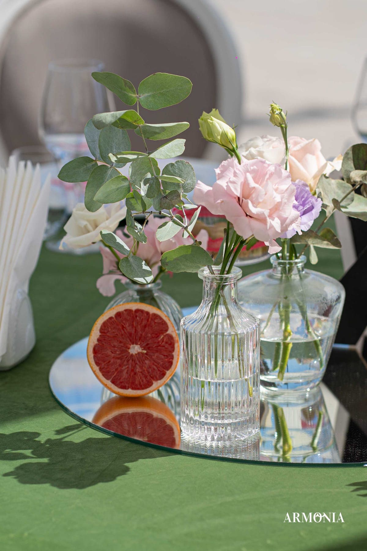 Detaliu floral pe oglindă — vaze de sticlă și jumătăți de grapefruit