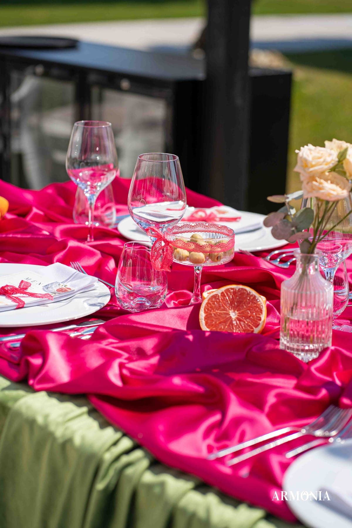 Detaliu — satin fucsia, pahare de cristal și felii de grapefruit