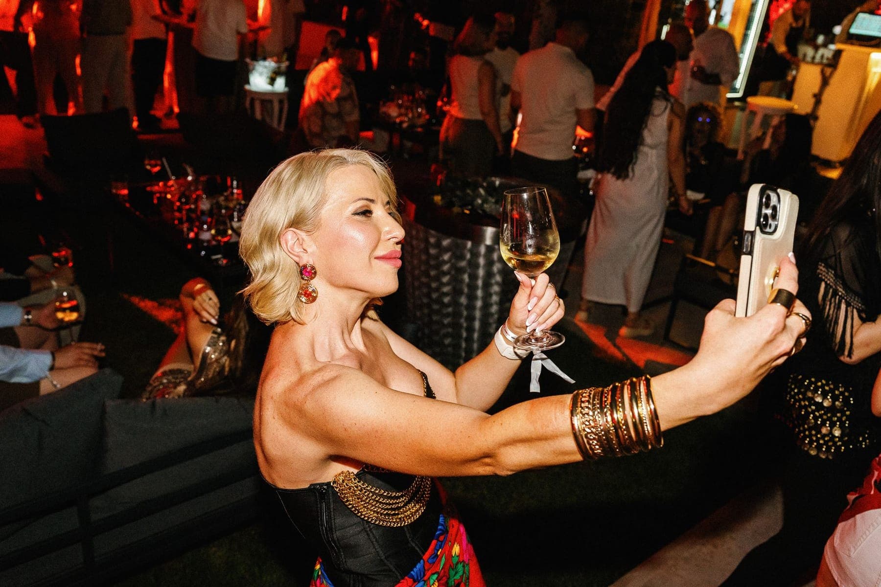 Invitată cu paharul de vin ridicat, în mulțime