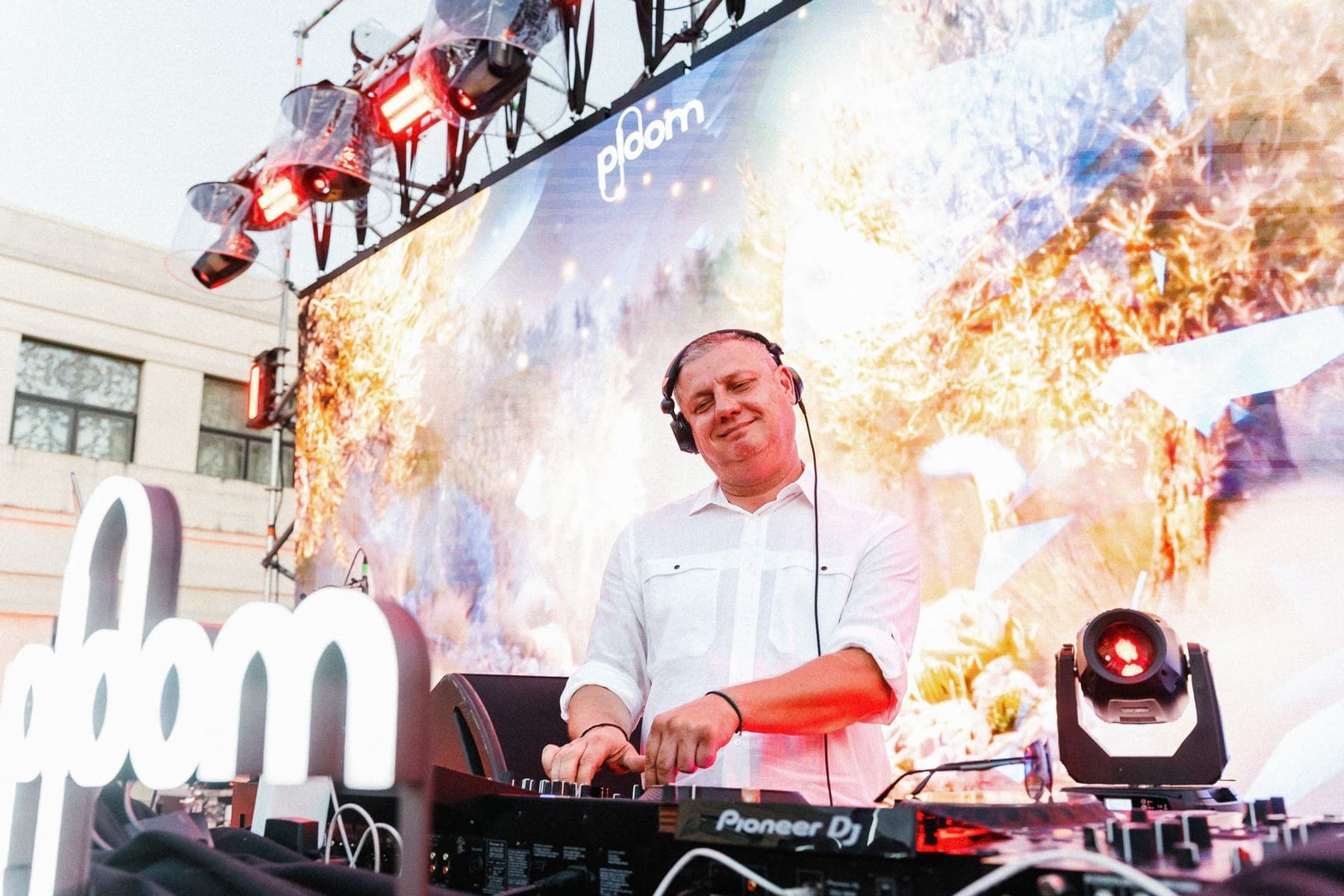 DJ la pupitru, cu proiecții de flăcări pe ecranul din spate