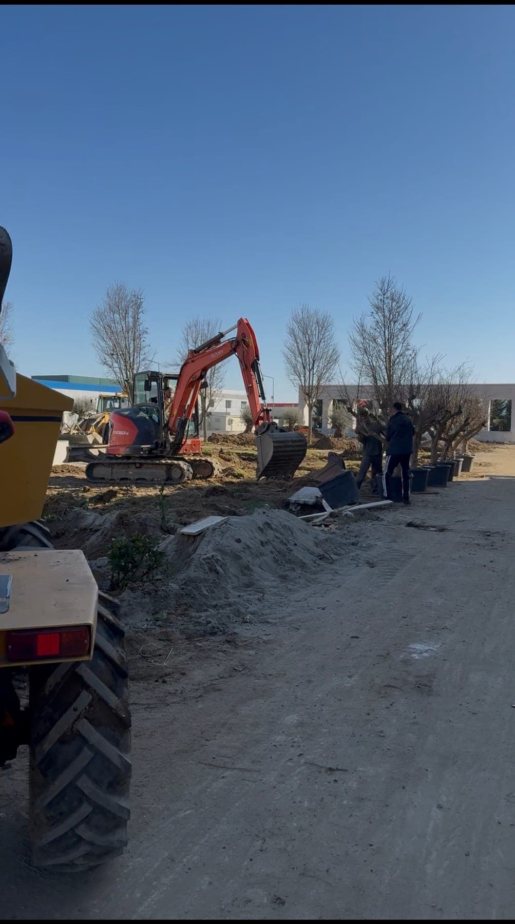 Excavator și utilaje pe șantierul grădinilor, printre movilele de pământ