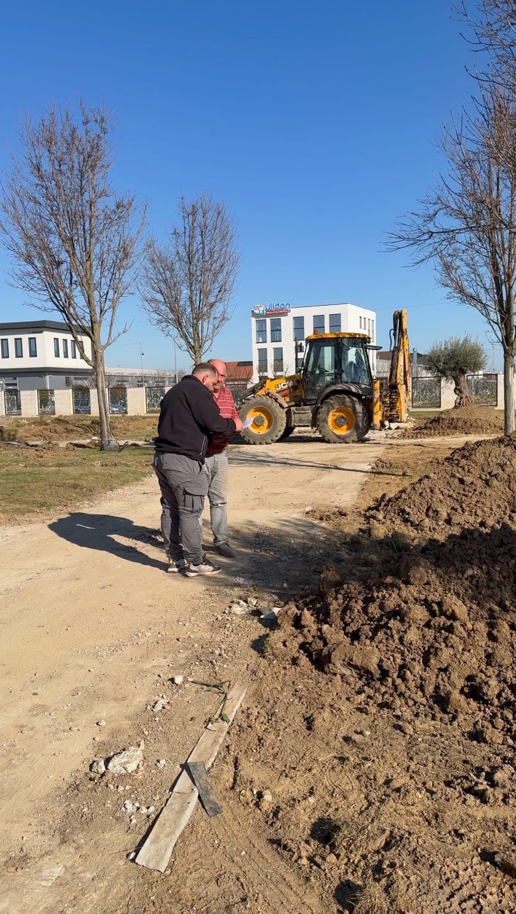 Utilaj săpând terenul pentru noile zone verzi, lângă clădire