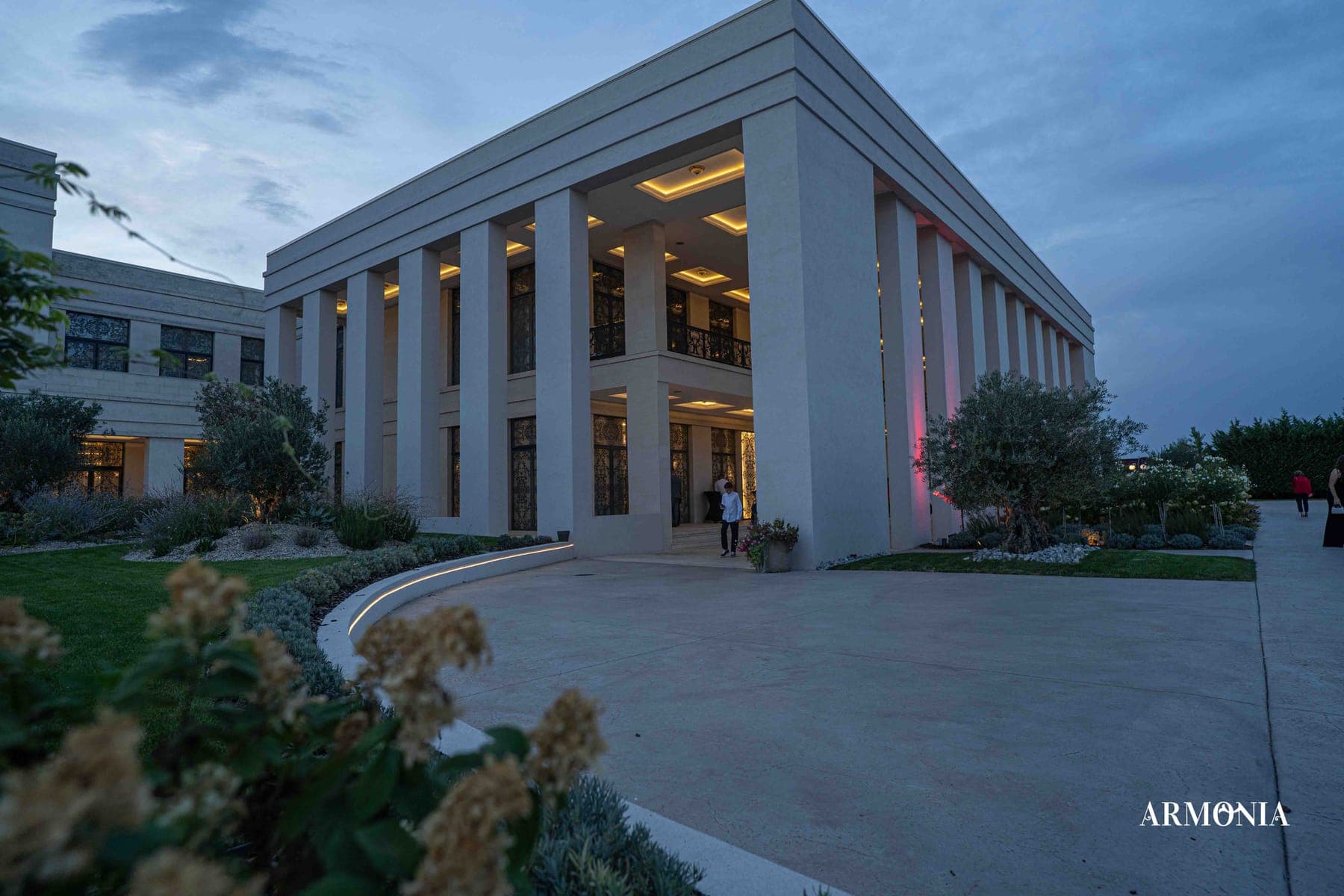 Intrarea principală luminată, cu gazonul curbat în fața colonadei