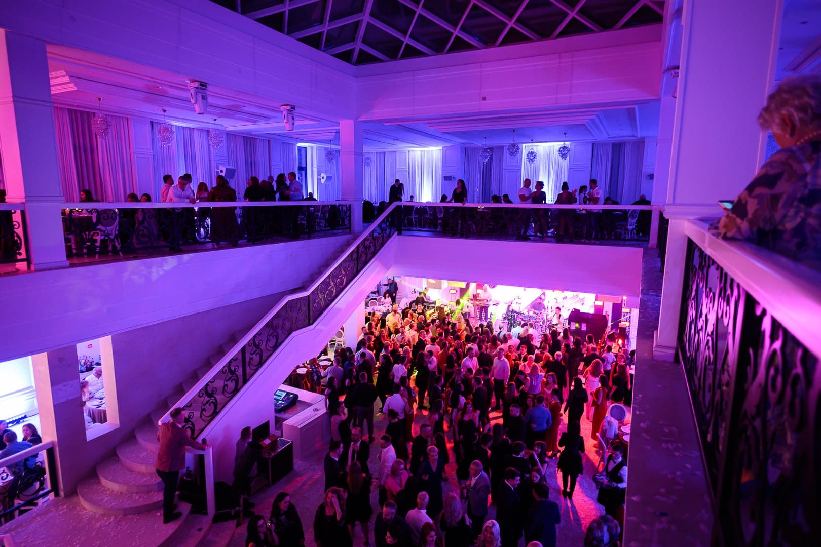 Privire de la mezanin peste sala plină, în lumini roz